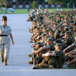 A US Marine Corps female Drill Instructor inspects the discipline of the recruits who are seated and lined up in platoon order during the annual Independence Day celebration at Parris Island. (Credit: U.S. National Archives)